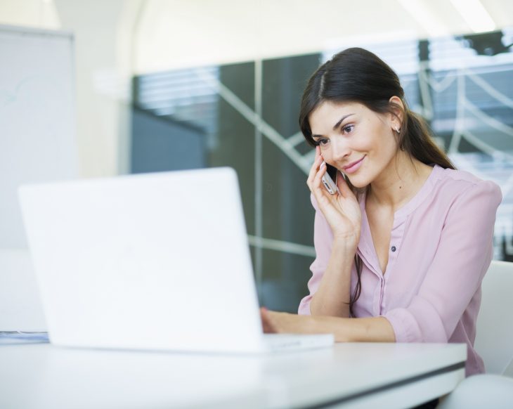 woman at laptop talking on mobile phone