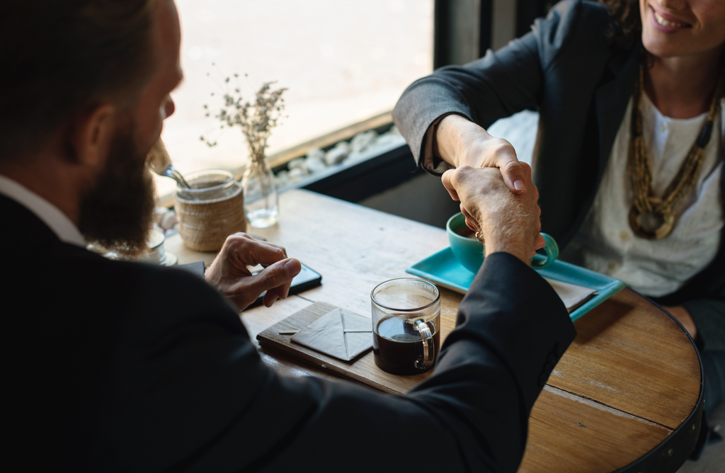 man and woman concluding a meeting over coffee shaking hands