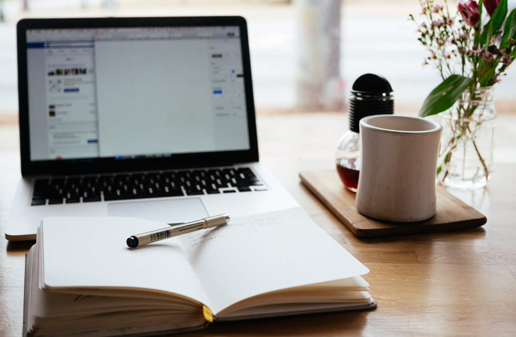 laptop book with pen on it, with coffee and honey in the background